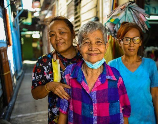 Three smiling senior women together at a local market